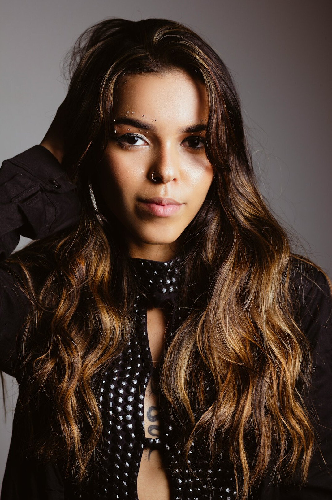 Studio portrait of a young Latina woman with wavy brown hair smiling
