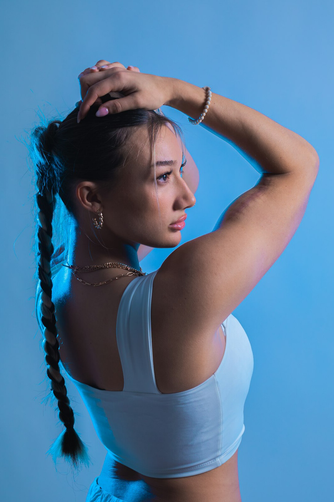 Studio portrait of a Latina woman in her late twenties with a ponytail wearing a white shirt